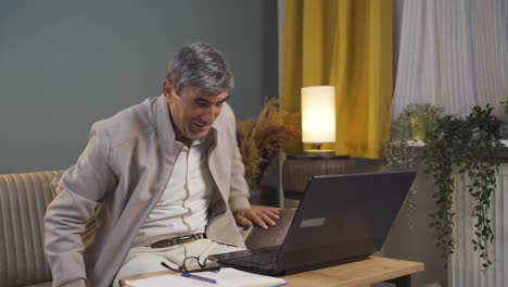 Old man looks at laptop and rejoices.