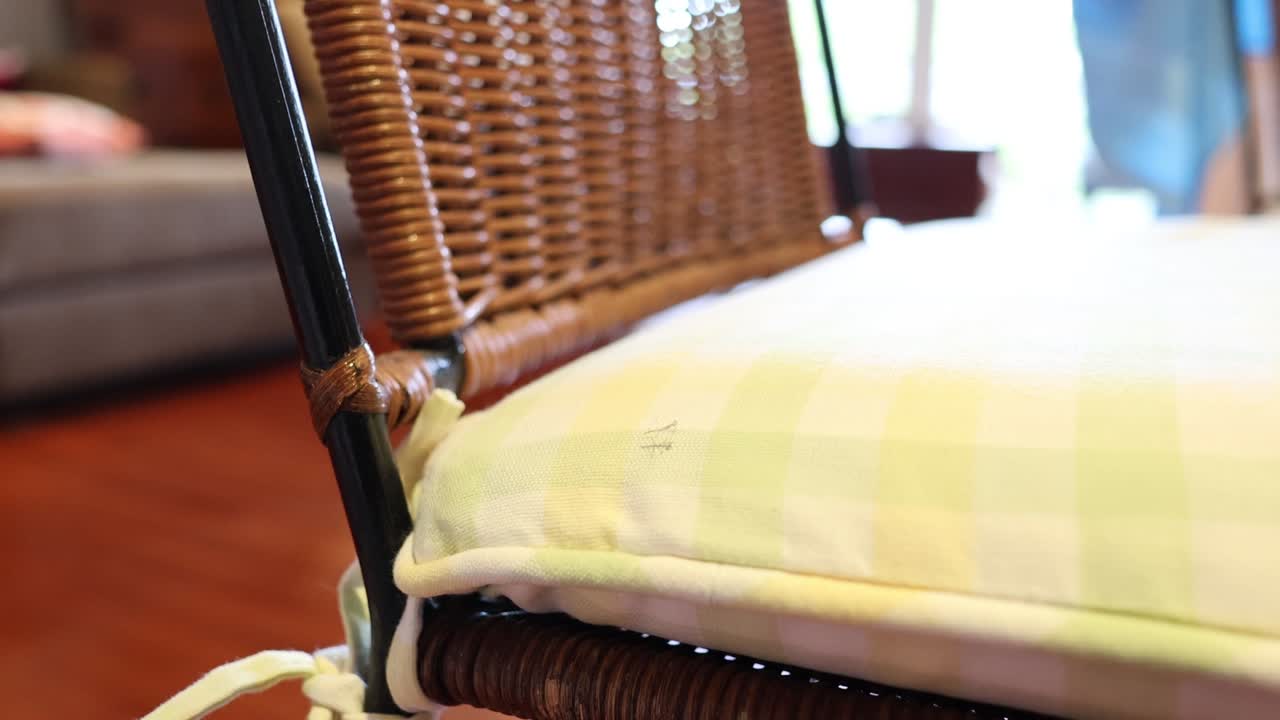 A hand fluffs a checkered pillow on a chair