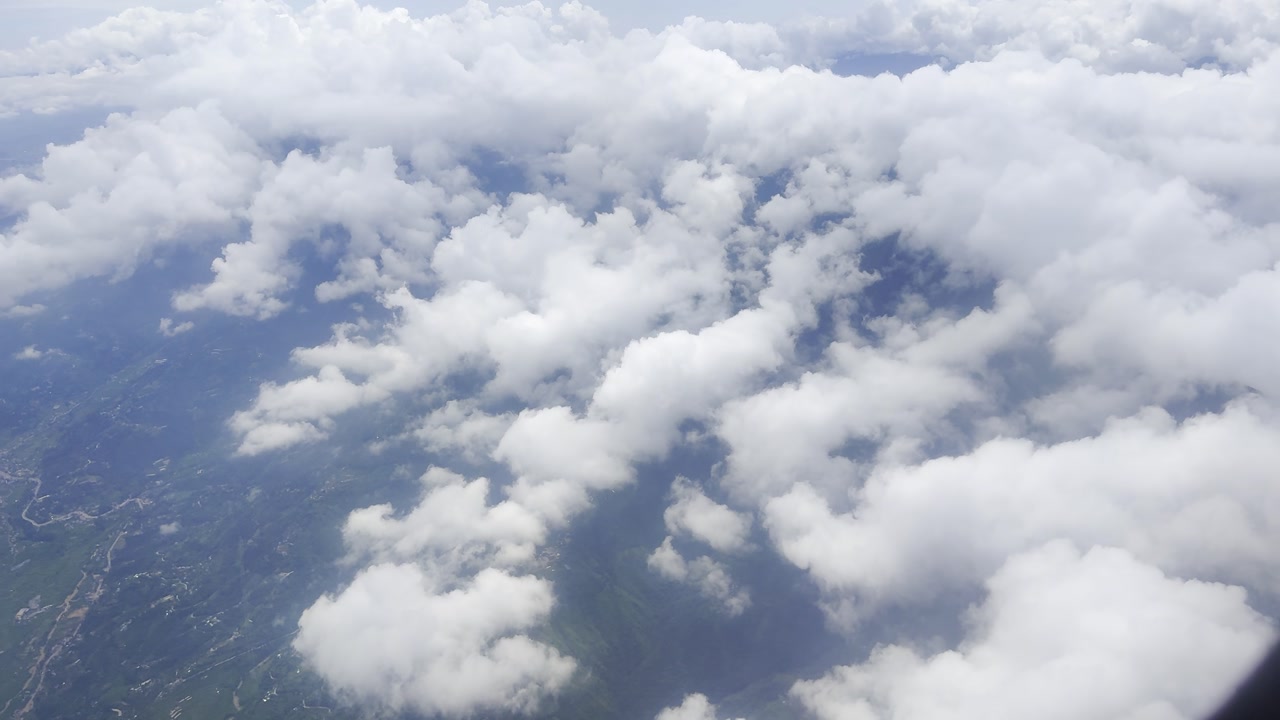 Footage of white clouds and sky in motion, captured from an airplane. Perfect for travel, aerial views, and nature projects, showcasing serene skies and dynamic movement above the landscape.