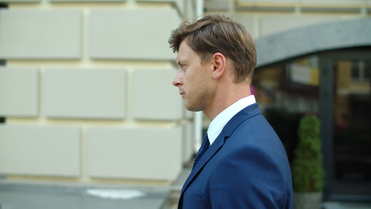 Side view business man walking outdoors. Executive man looking ahead at street