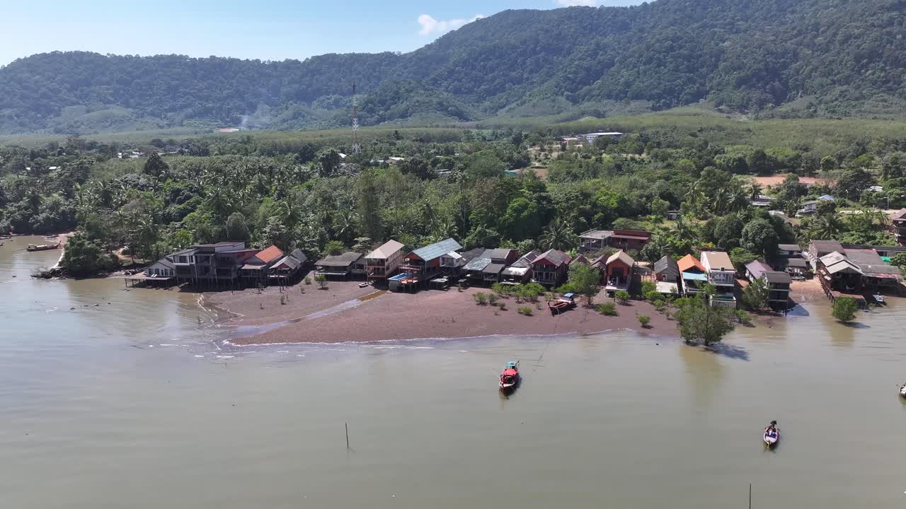 Old town Koh Lanta, wooden buildings with shops and restaurants on seaside, mountain background.