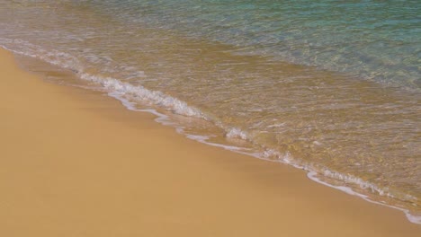 Gently-clear-water-waves-in-slow-motion-rolling-into-empty-sandy-beach,-180fps