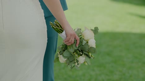 la novia sosteniendo un ramo de flores blancas, de pie al lado del novio, destacando un momento de boda sereno