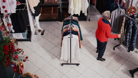 Top-down-view-of-clients-walking-around-bustling-shopping-mall-fashion-shop-aisles,-looking-to-purchase-clothes-as-presents-for-family-and-friends-during-Christmas-promotional-sales-event