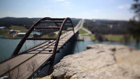 austin pennybacker bridge  tilt-shifted time-lapse, focus tilted to highlight narrow segment of ledge - front part of bridge. traffic is heavy on north side, it slows down but never fully stops.