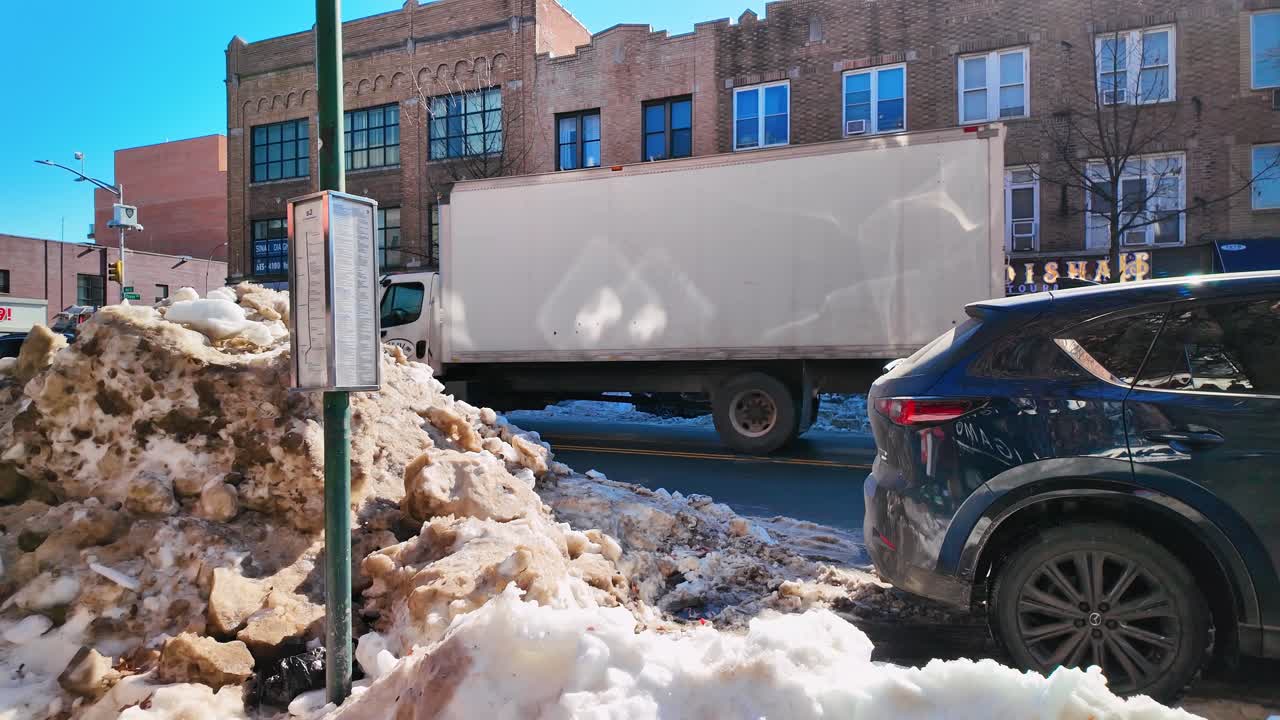 New York, USA, 25. december 2025: Stor bunke snavset sne ved en bybusholdeplads. Snavset sneophobning på en gade i New York City ved siden af et busplanstavle og en varevogn.