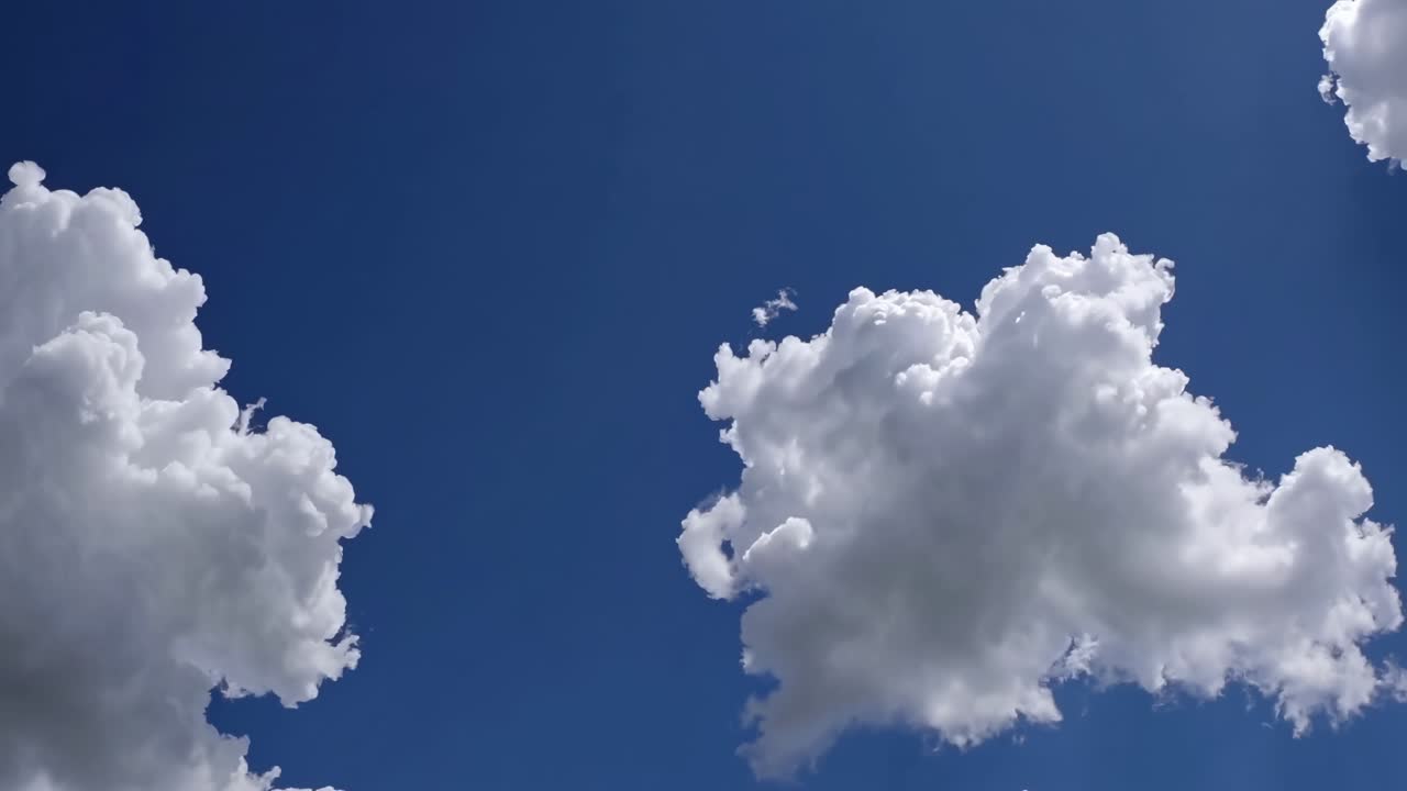 深青色の空を背景に、ふわふわとした白い雲をローアングルから捉えた動画。
