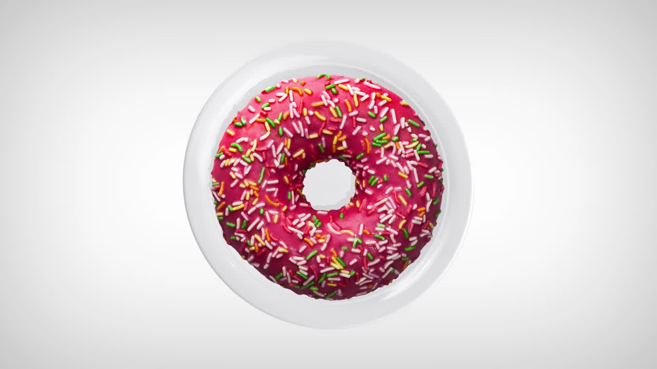 deliciosa rosquilla con salpicaduras coloridas, girando en un plato blanco. rosquilla de primer plano. vista de arriba.