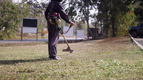 person trimming grass with a string trimmer