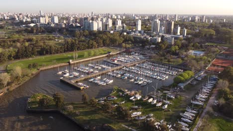 Vista-Aérea-Sobre-El-Club-Náutico-Olivos-Al-Atardecer-Y-La-Ciudad-De-Buenos-Aires-Que-Se-Aproxima-Al-Fondo