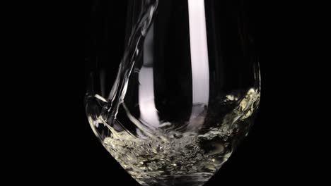 pouring delicious white wine into wineglass isolated on black background