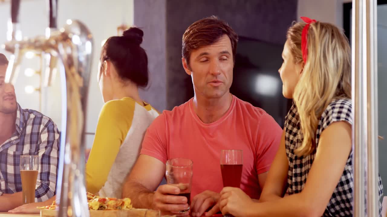 amigos interactuando entre sí mientras toman un vaso de cerveza 4k