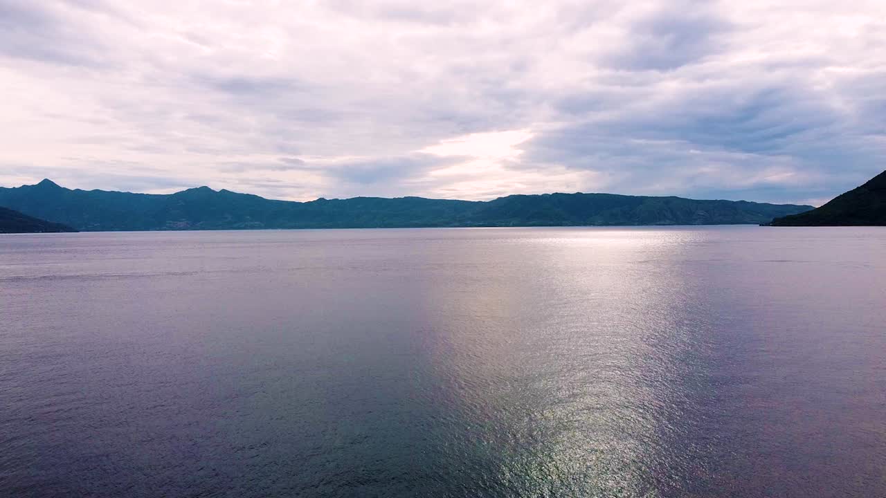 인도네시아 동부 누사 텐가라의 알로르 섬에서 황혼의 분홍색과 보라색의 흐릿한 일몰과 함께 바다 위로 떠오르는 항공 드론