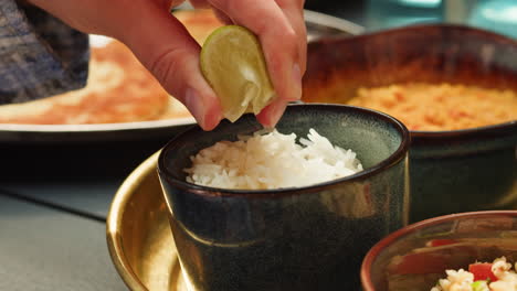person squeezing lime on rice with other dishes