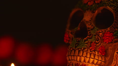 close up on still life of decorated skull lit by candles celebrating mexican holiday of dia de muertos or day of the dead 1