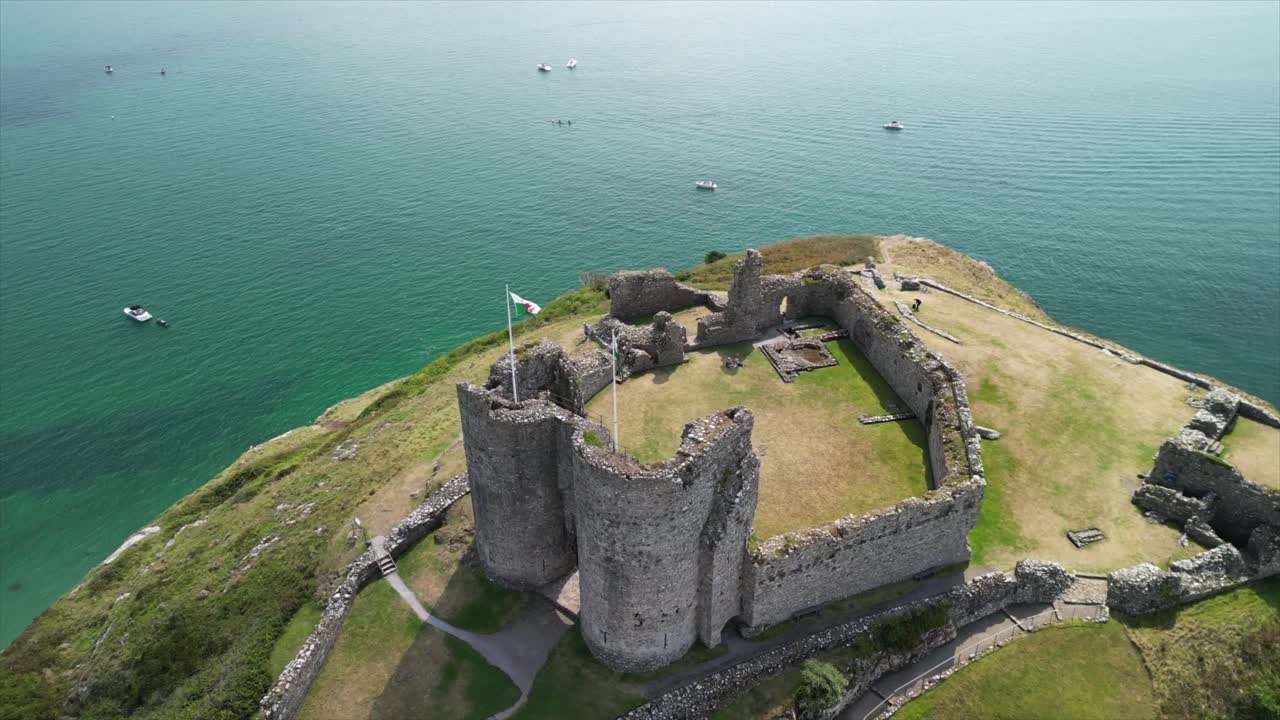 Stunning Criccieth Castle on a lovely summer afternoon - aerial drone clockwise rotate from above, moving out to reveal scenery - North Wales, UK
