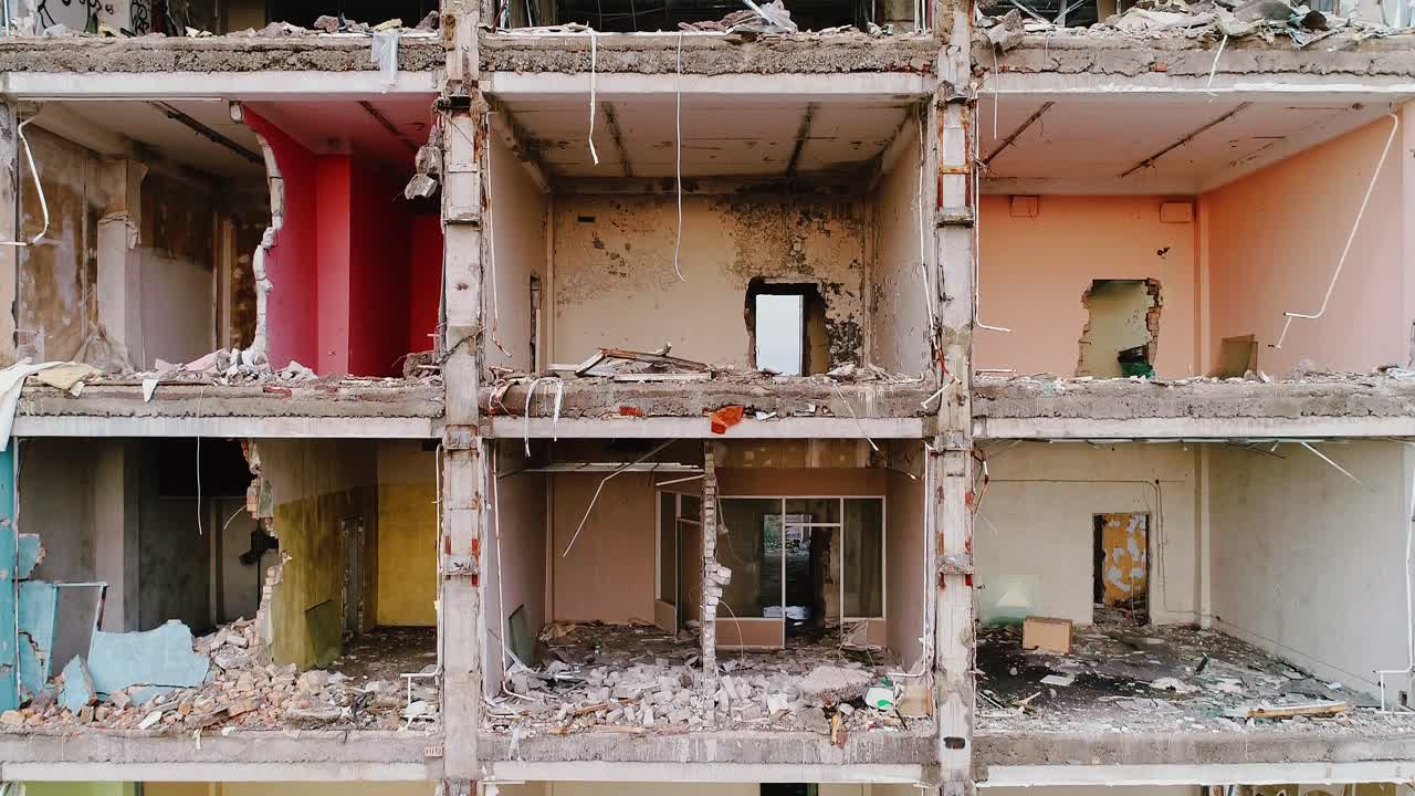 Dramatic reveal of destruction as drone flies down crumbling apartment facade