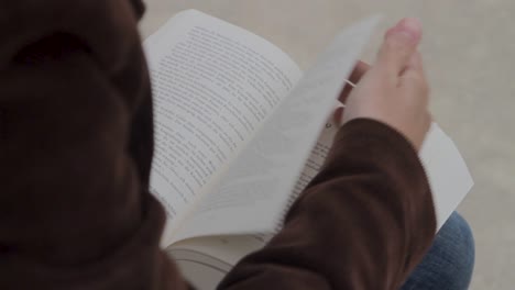 Over-the-shoulder-shot-of-person-flipping-through-book-pages