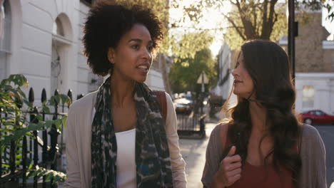 two beautiful friends walking using smart phone technology in sunny city