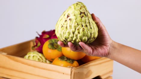 hand placing custard apple in fruit basket