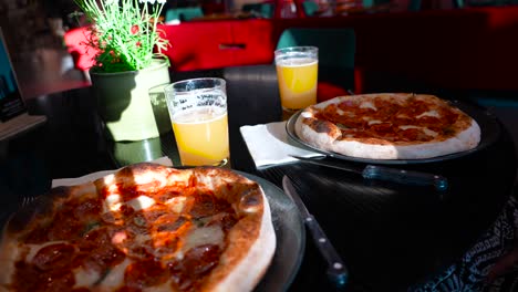 Footage-displays-two-pepperoni-pizzas-on-a-table-with-cheese-and-two-glasses-of-cold-beer-in-a-restaurant-in-Tallinn-Estonia,-located-in-Europe-Baltics-in-4K