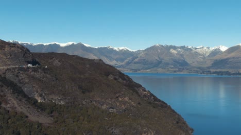 drone reveal of mountain surrounded lake in queenstown new zealand