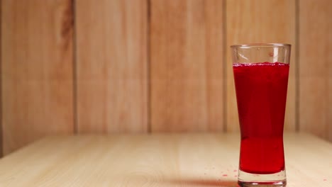 a glass of red soft drink on table