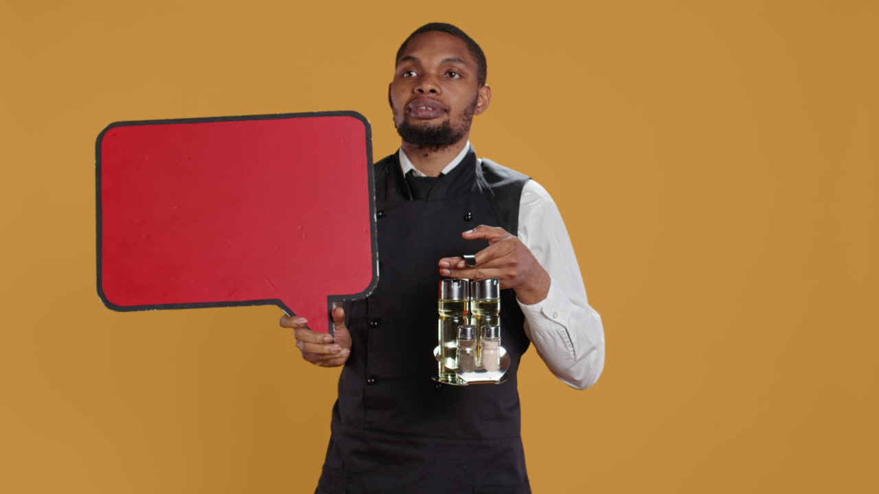 empleado de catering mostrando un icono de burbuja de habla roja en el estudio