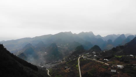 aerial over winding road with misty hills in distant at ha giang, vietnam