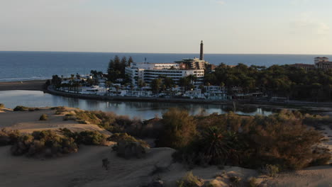 drone flying low and rotating to take shot of the city by the sea surrounded by sandy beach