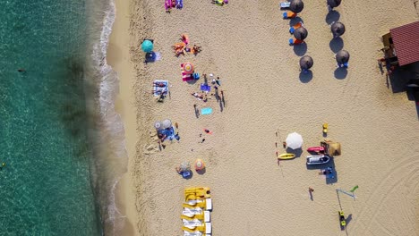 Playa-De-Cala-Mesquida-Con-Coloridas-Tumbonas-Y-Sombrillas,-Isla-De-Mallorca,-España,-Día-Soleado,-Vista-Aérea