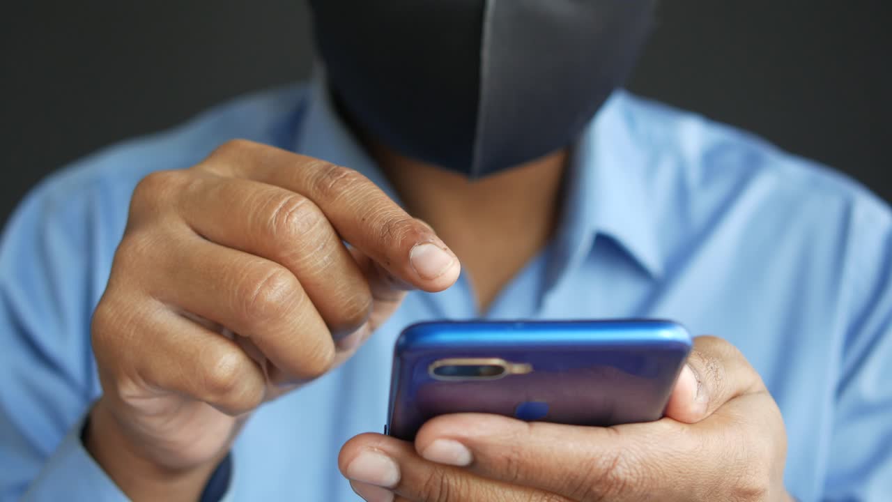Persona che usa lo smartphone mentre indossa una mascherina