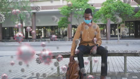 multiple covid-19 cells floating against man wearing face mask checking time while sitting on bench