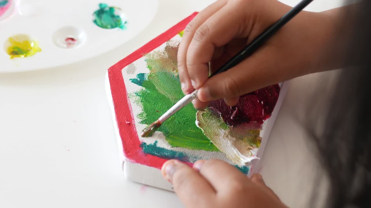 Child painting a small hexagon shaped canvas