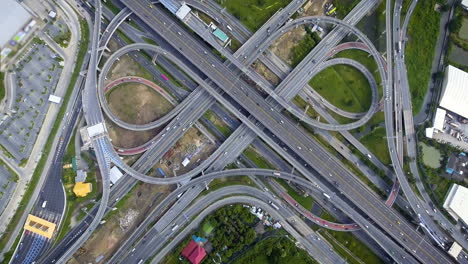 Vista-Aérea-Del-Cruce-De-Carreteras-Con-Tráfico-Urbano-Intenso-Acelerando-En-La-Carretera