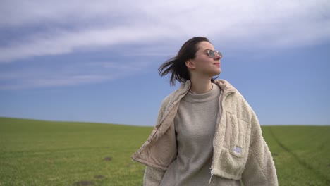 a young beautiful brunette girl walks through a green meadow.