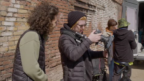 two production co workers setting up a camera in the street and other two workers taking material for a recording from a van 3