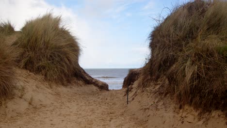 Blick-Durch-Die-Sanddünen-Mit-Dem-Meer-Im-Hintergrund-Am-Strand-Von-Hemsby,-Weitwinkelaufnahme-Der-Küstenerosion