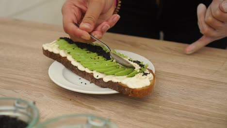 Slowmo---Preparar-Aguacate-En-Pan-Tostado-Con-Semillas-De-Sésamo-Blanco-Y-Negro-Y-Hummus