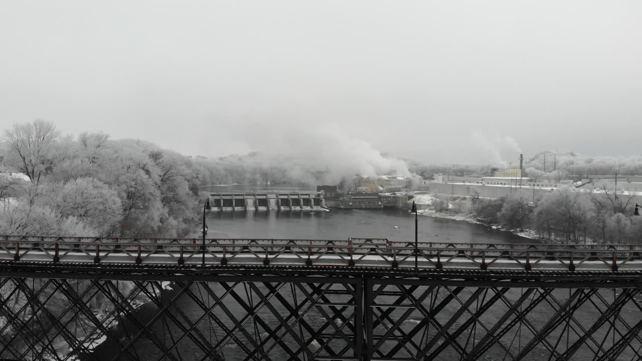 서리가 덮인 나무로 둘러싸인 겨울의 다리와 강 댐