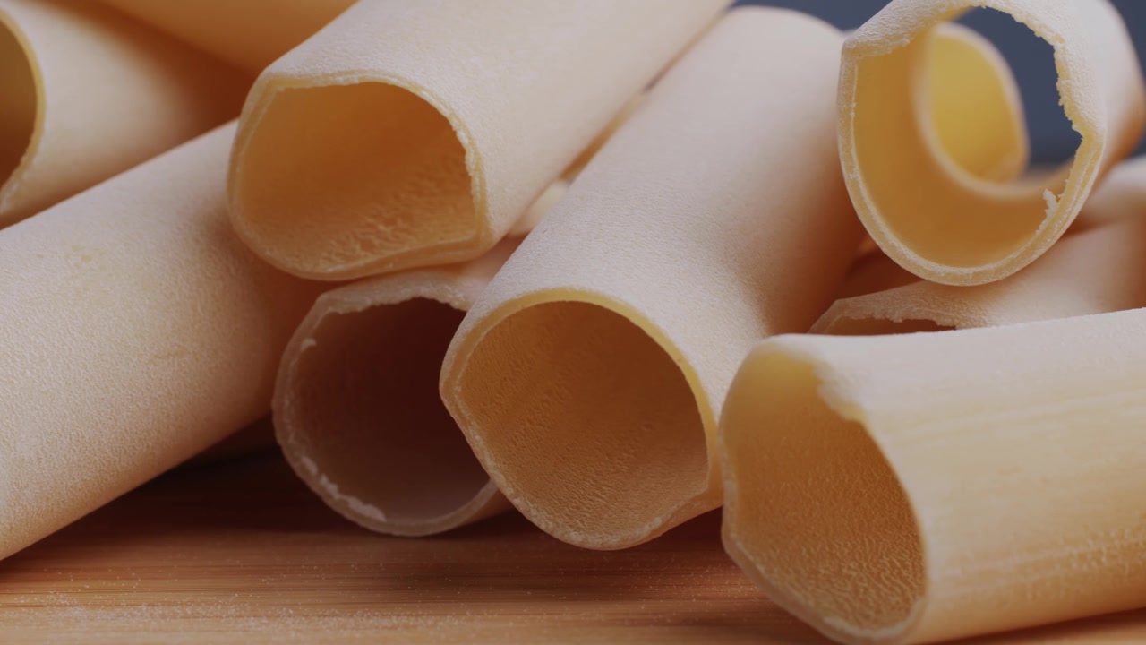 Primer plano de pasta de canelones cruda sobre una superficie de madera