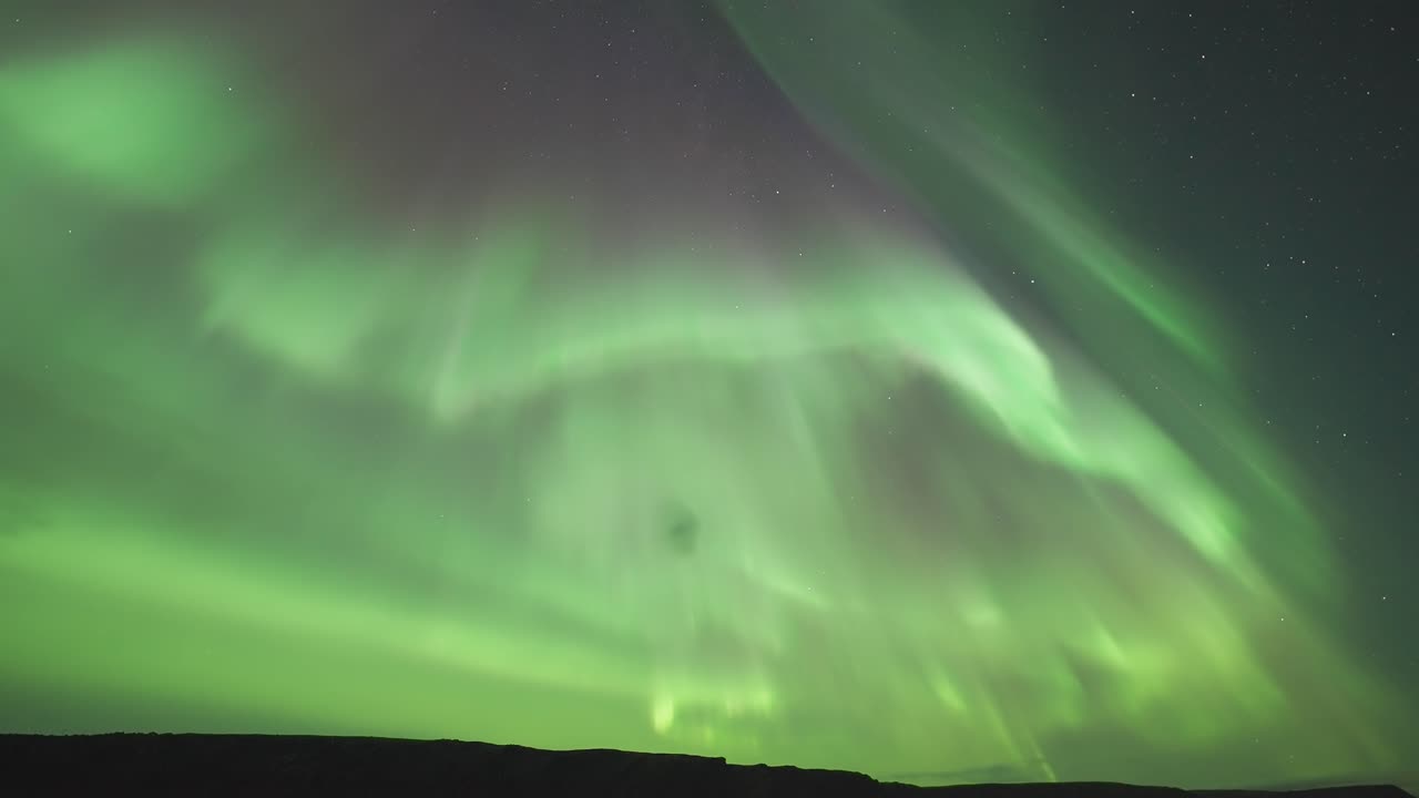 un video de lapso de tiempo que muestra la impresionante aurora boreal mientras se mueve con gracia sobre un fiordo tranquilo durante una oscura noche de invierno