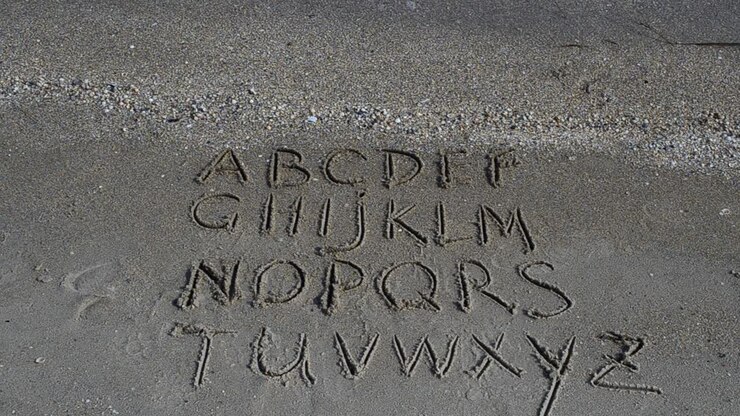 Alfabeto inglese scritto sulla sabbia della spiaggia. Ripresa sulla spiaggia
