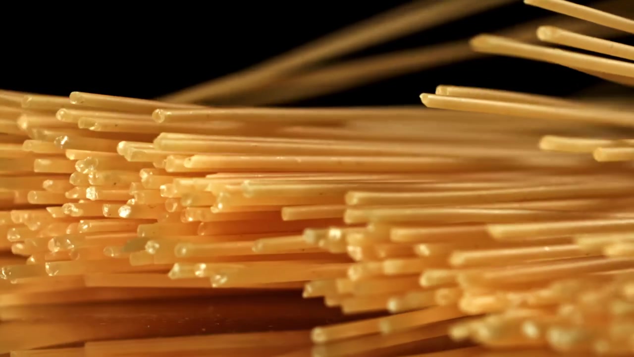 Spaghetti secchi che cadono al rallentatore su sfondo nero