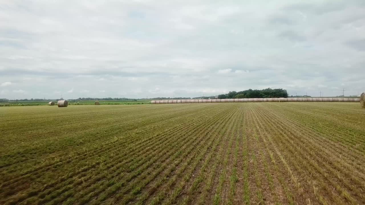 Low flyover of harvest hay field and sweeping views of corn fields in rural South Dakota