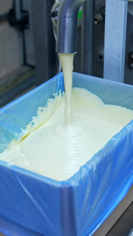 liquid butter is pouring from the pipe into the container. factory for the production of butter. automated line. food production.. vertical video