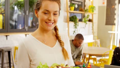 portrait of beautiful waitress holding salad in plate 4k