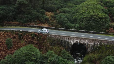 aerial view of ancient bridge with a car driving by in the knockmealdown mountains of clogheen, tipperary, ireland