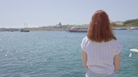 young woman sitting and watching the boats in the grand harbor, valletta malta