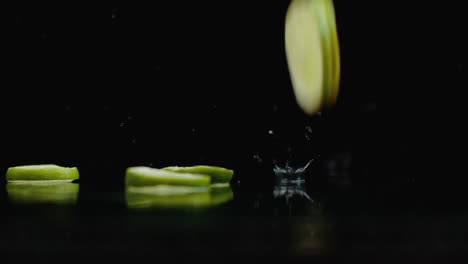 rings of fresh green lime sliced fall on the glass with splashes of water in slow motion.